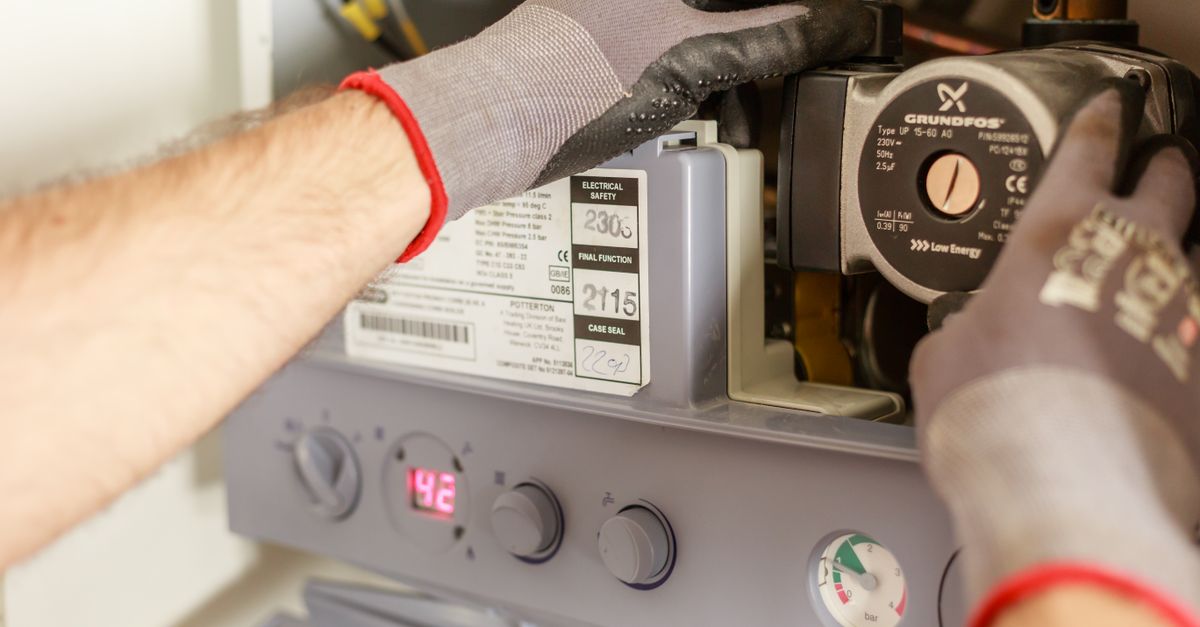 Heating engineer servicing a wall-mounted boiler